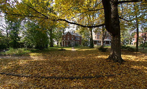 A cozy and charming house is beautifully surrounded by rich, red and orange autumn leaves.